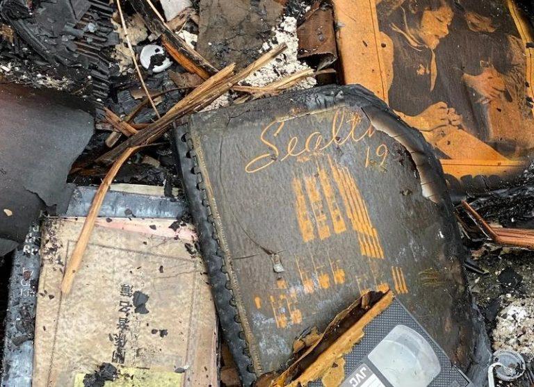 A burned book says Seattle and has a date beginning in 19 on it surrounded by other burned items