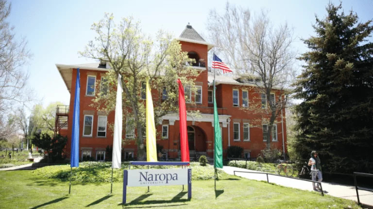 An image of a brick building with grass in front and a sign saying Naropa