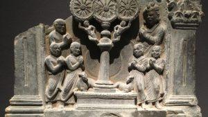 ancient stone image of Buddha's disciples around a pillar