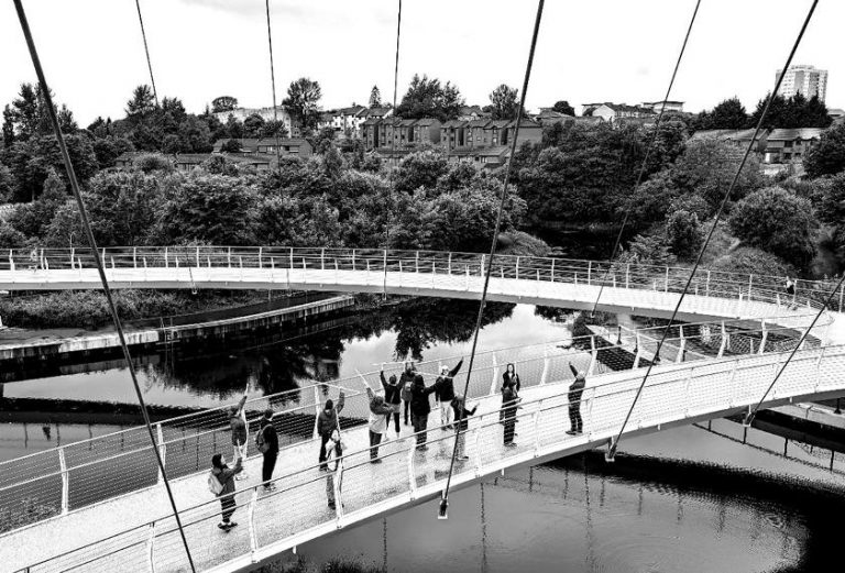 people on a bridge over a river in black and white