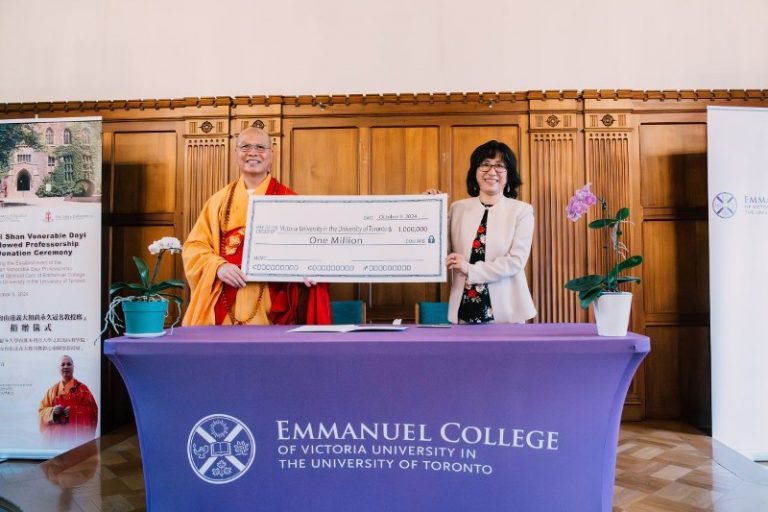 a monastic and a laywoman hold a large check for the audience